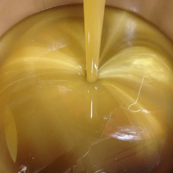 raw honey pouring into a bulk drum